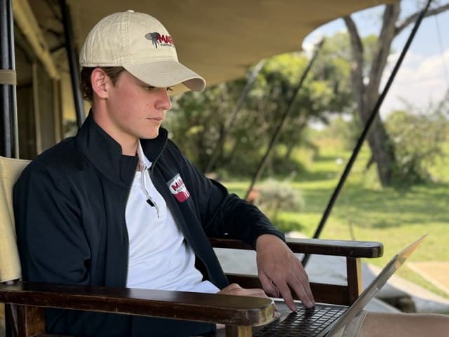 Will May working on a laptop at a camp in the Masai Mara